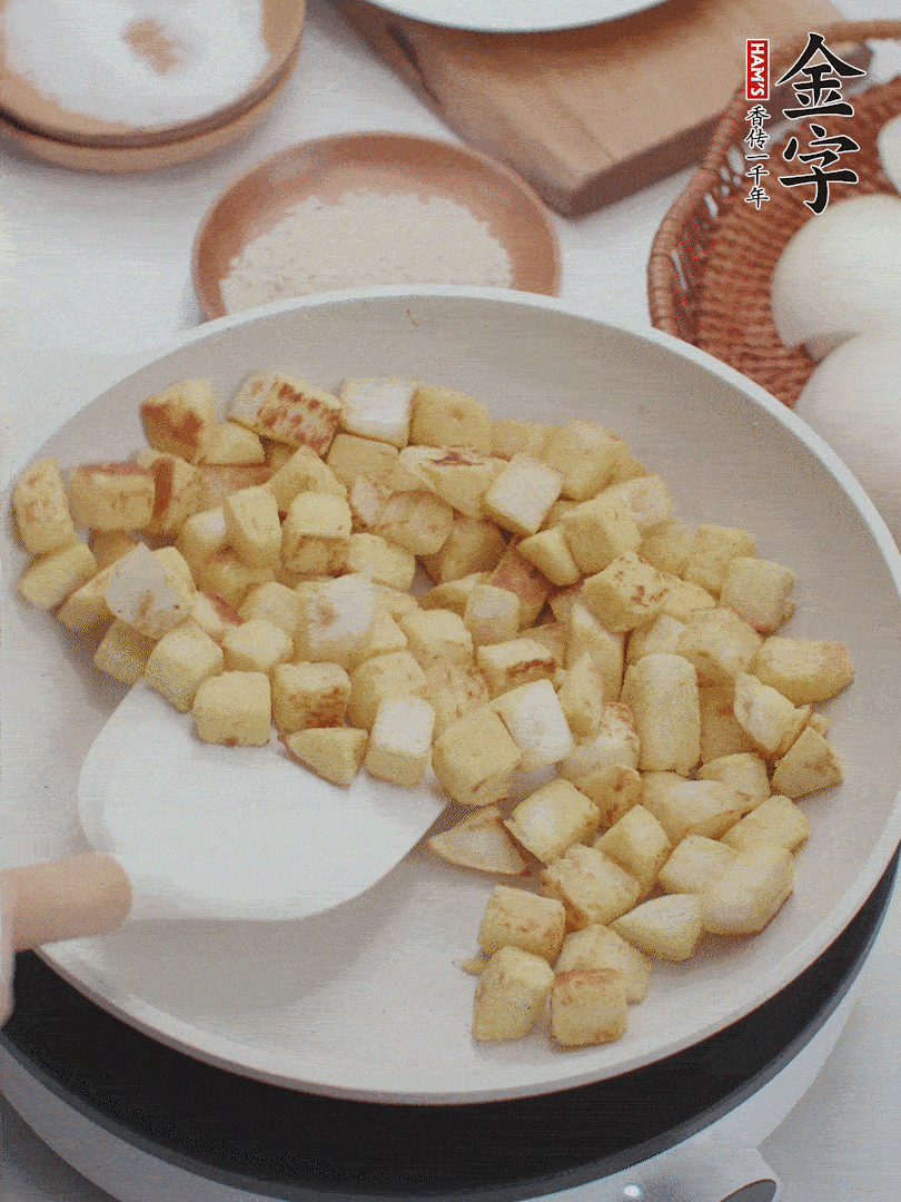 起鍋熱油，倒入饅頭丁，小火煎至蛋液凝固定型再翻面，饅頭丁部煎至金黃時(shí)盛起待用。