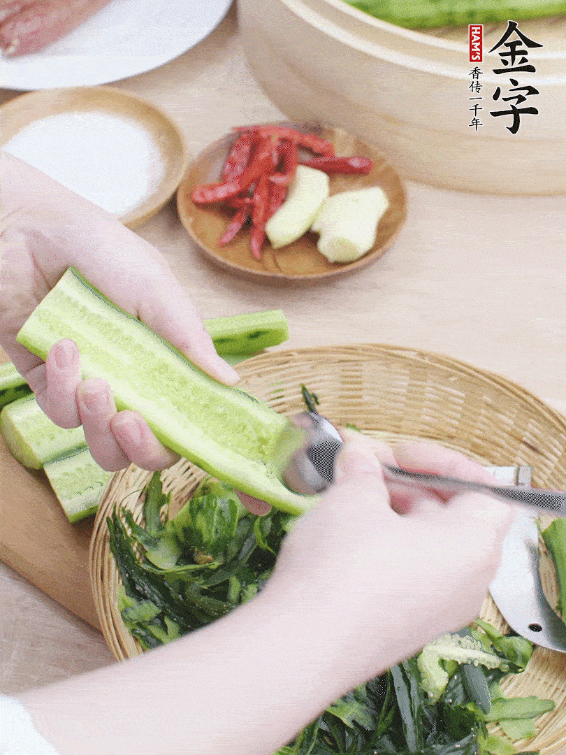 黃瓜削皮，對半切開，勺子挖去內(nèi)瓤，斜刀切片。青蒜斜刀切段。