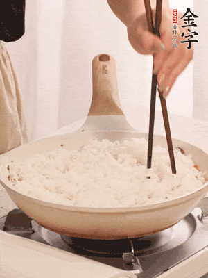 把瀝干水分的米飯均勻鋪在上面，筷子戳幾個(gè)洞，以便透氣，轉(zhuǎn)小火蓋上蓋子燜至水分收干，大概10分鐘。